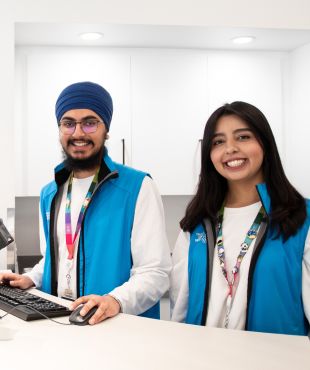 Two Calgary Public Library staff at a desk smiling.
