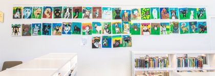 A photograph of pastel drawings of different dogs hung up on a wall at Central Library. 