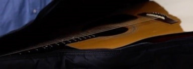 A visual of an acoustic guitar in its case. 