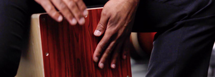 A picture of someone playing the Cajon Box Drum. 