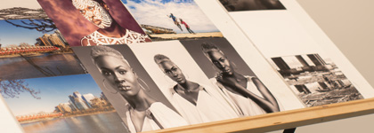 A photograph of an easel that has different pictures of locations and people glued to a poster board on it. 