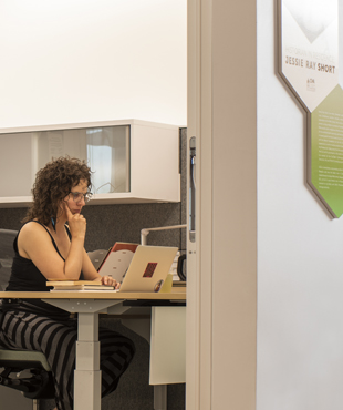 A visual of the Historian in Residence office, with Jessie Ray Short sitting in it and working on a computer.
