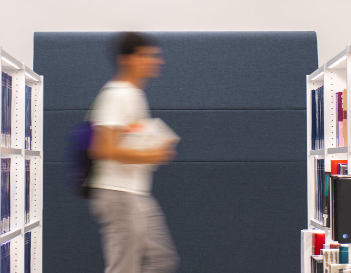 background image: This is a photograph of an individual who is blurred to show movement,  walking with a book.
