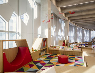 This is a photograph of the Early Learning Centre at Central. In the picture, there is a rug with a triangle of different colours. There is a red circle ottoman in the centre.