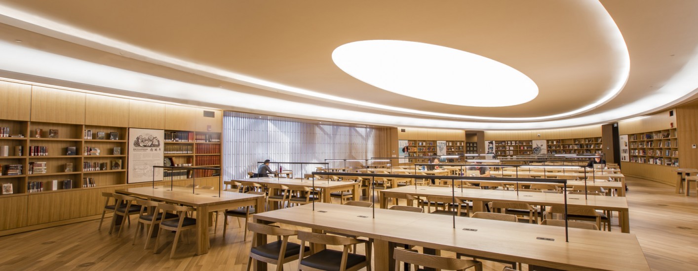 A photography of the TD Great Reading Room. Wood-paneled walls and special collections surround long tables. 