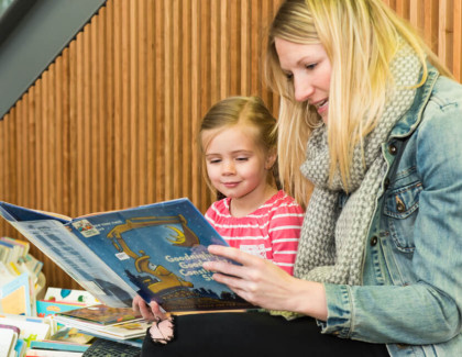 Photograph of a woman and a child reading together. 