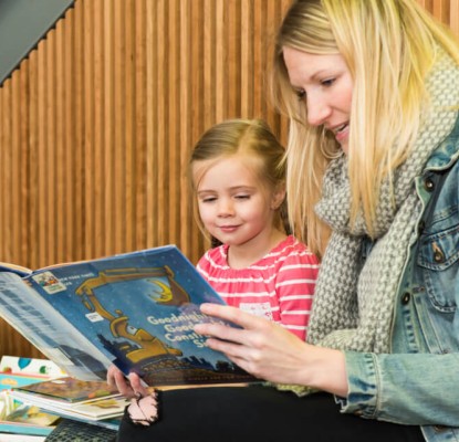 Photograph of a woman and a child reading together. 