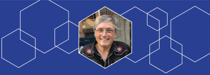Photograph of 2026 Creative: AI Collaborative Artist in Residence Paul Freeman surrounded with blue and white hexagon graphics