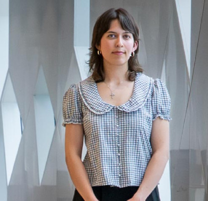 A person stands beside tall geometric windows inside Central Library. The person is the 2026 Historian in Residence. 