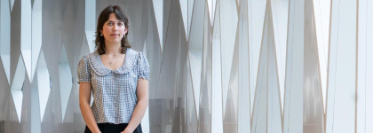 A person stands beside tall geometric windows inside Central Library. The person is the 2026 Historian in Residence. 
