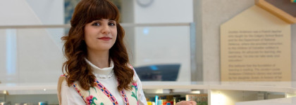 Photo of Maedeh Mosaverzadeh, 2026 Newcomer Artist in Residence, inside a Library near an exhibit display and bookshelves. 
