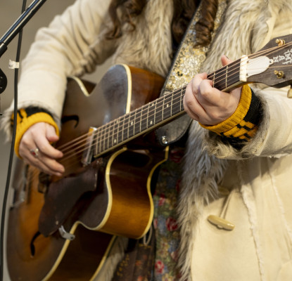 Rozsa Arts performer holding a guitar with a microphone stand