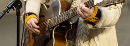 Rozsa Arts performer holding a guitar with a microphone stand