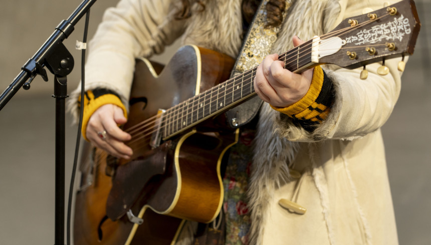 Rozsa Arts performer holding a guitar with a microphone stand