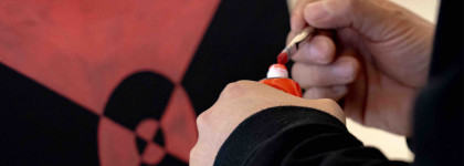 Indigenous Artist in Residence Darren Weaselchild's hands painting a read and black painting