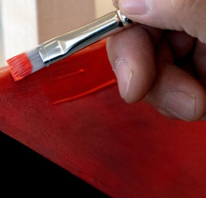 Indigenous Artist in Residence Darren Weaselchild's hands painting a read and black painting