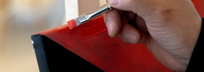Indigenous Artist in Residence Darren Weaselchild's hands painting a read and black painting