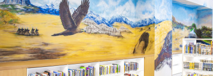 This is a picture of a mural. The mural depicts a prairie landscape. A bald eagle is flying, and teepees are in the background. 