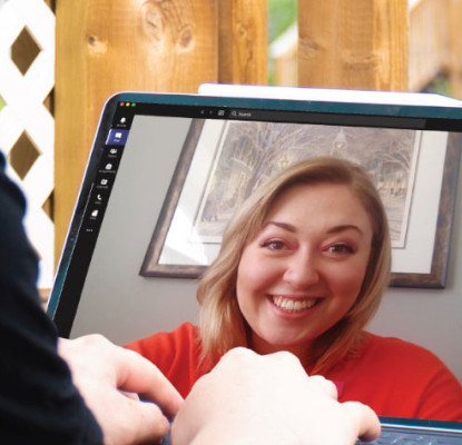 A person engaged in a virtual meeting on a laptop while sitting on a deck outside.