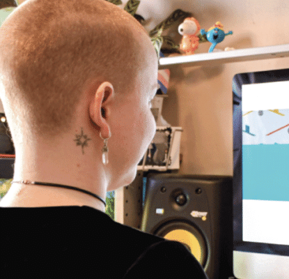 Photograph of a person sitting in front of a desktop computer screen. 