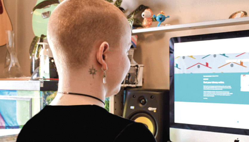Photograph of a person sitting in front of a desktop computer screen. 
