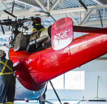 Photograph of a two individuals working on a red helicopter.