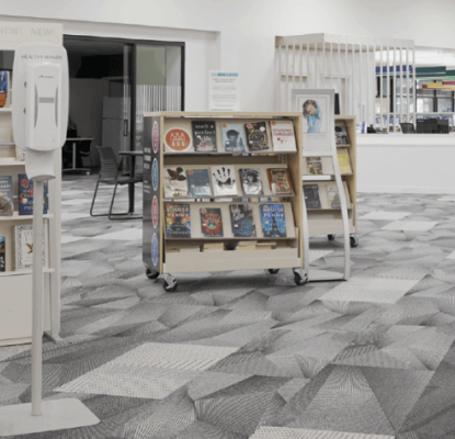 Photograph of the interior of a Calgary Public Library location. On the photo are illustrations of red flowers. 