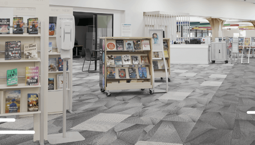 Photograph of the interior of a Calgary Public Library location. On the photo are illustrations of red flowers. 