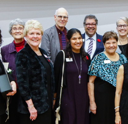 A large group of smiling people wearing nametags and colourful lanyards.