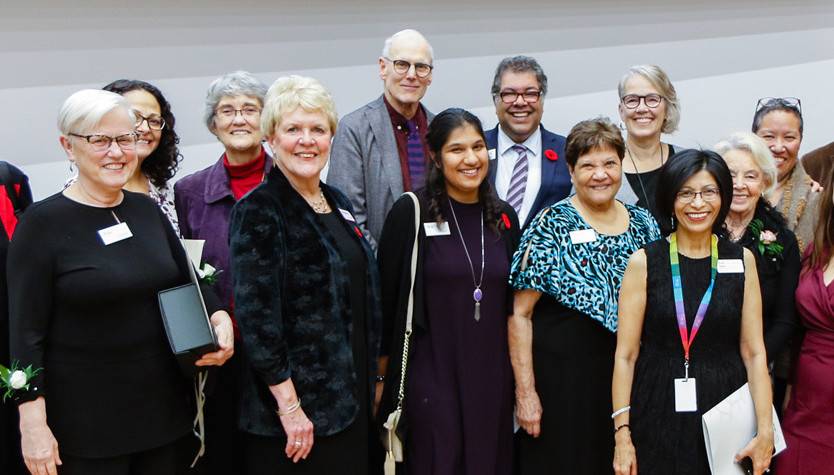 A large group of smiling people wearing nametags and colourful lanyards.
