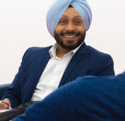 Two men speaking. One is smiling and writing in a notebook.