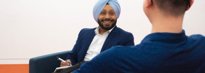 Two men speaking. One is smiling and writing in a notebook.