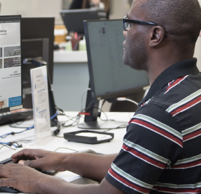 Photograph of two individuals working on desktop computers. 