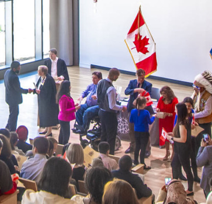 An audience watches a small group of people taking part in a citizenship ceremony