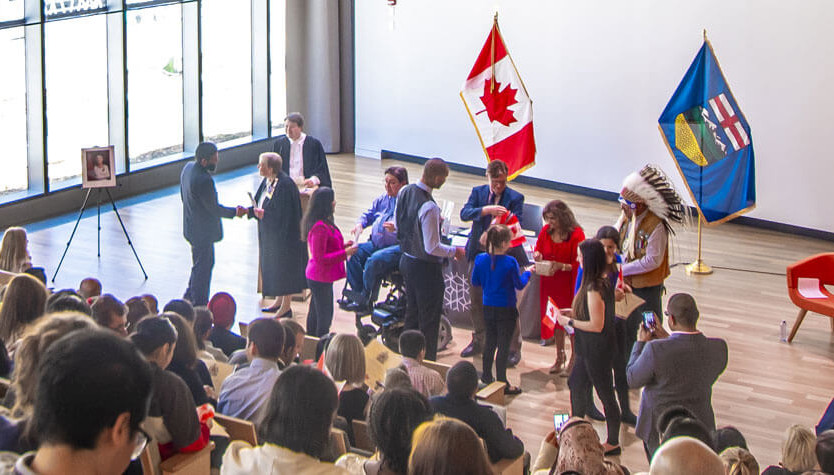 An audience watches a small group of people taking part in a citizenship ceremony