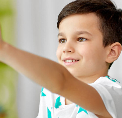 Photograph of a child holding up a toy in front of them. 