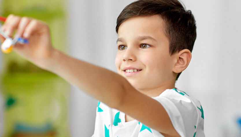 Photograph of a child holding up a toy in front of them. 