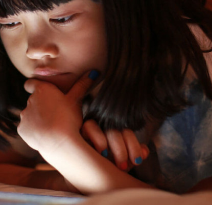 A child reading on a tablet. 