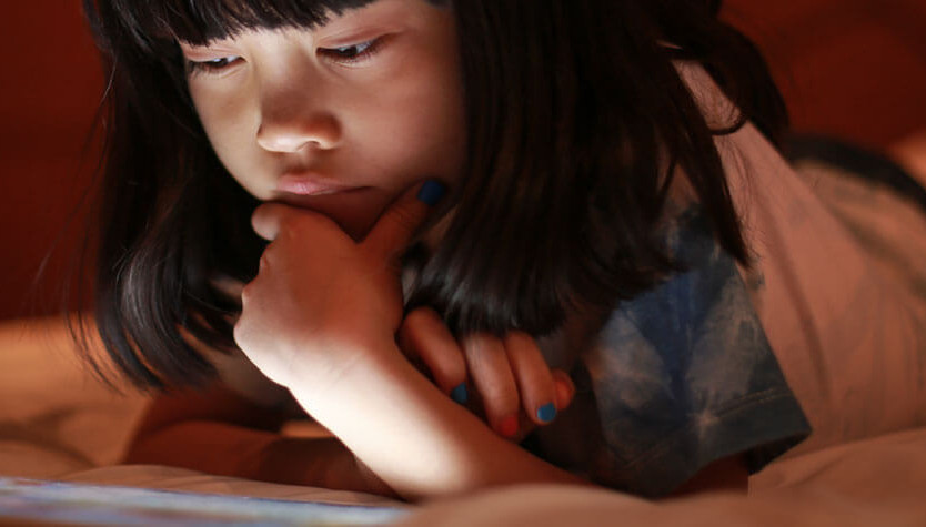 A child reading on a tablet. 
