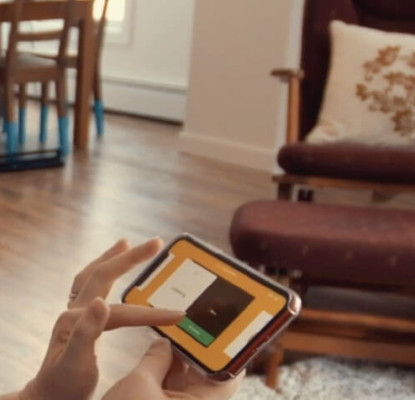 Photograph of an individual sitting in a home setting. They are using a smartphone application. 