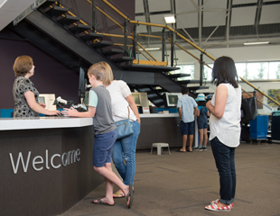 Library members standing around a welcome desk and talking to a staff member.