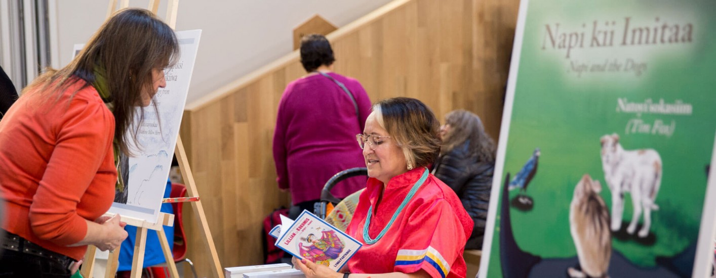 A photograph of an author reading out loud and talking with a patron.