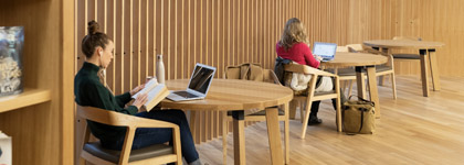 Three round tables with people sitting at a computer or reading.