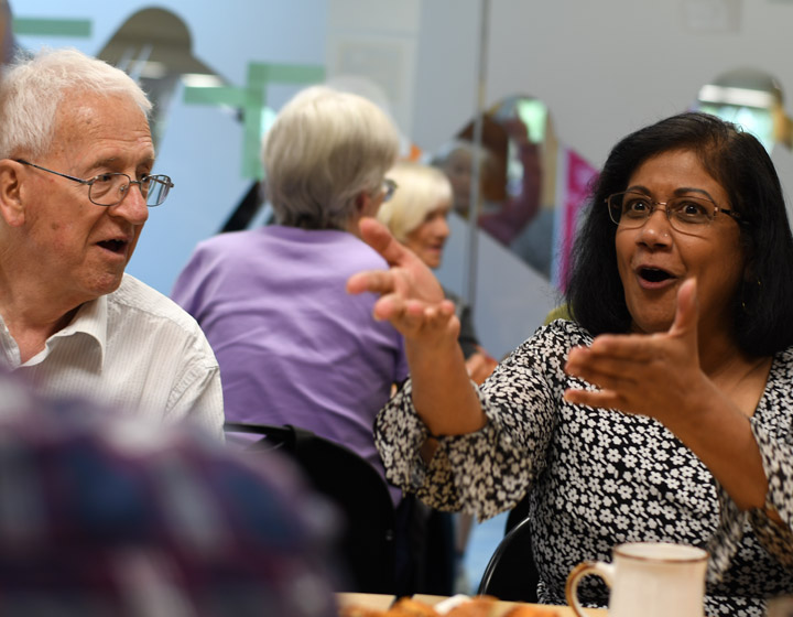 background image: A image of people sitting around a table and chatting.