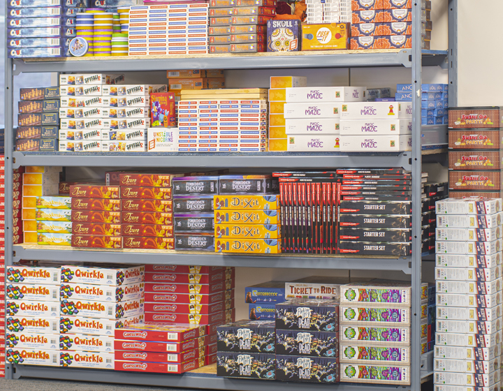 background image: A large shelf with stacks of board games.