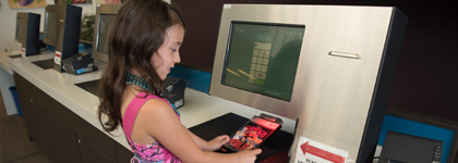 A young girl scans a library book at a self checkout.