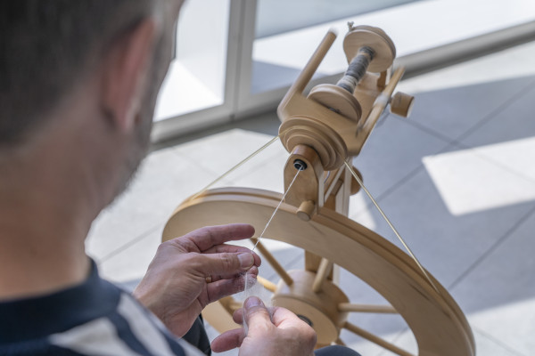 A man is using a spinning wheel.