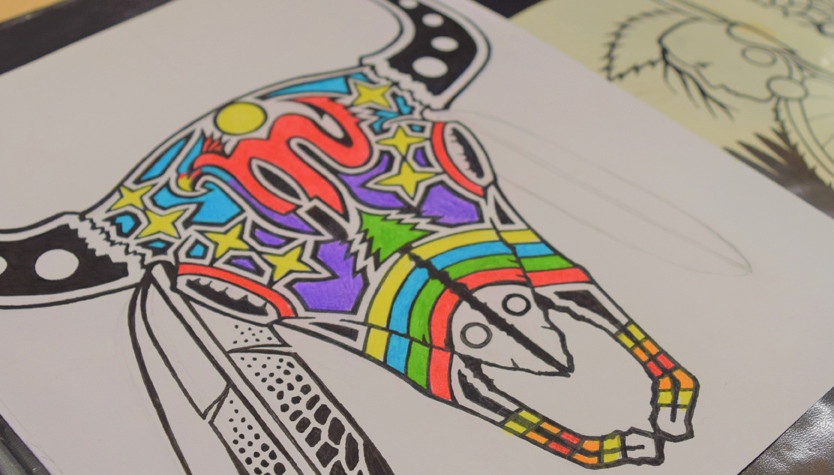 A colourful artistic drawing of a bison skull in a book on a table.