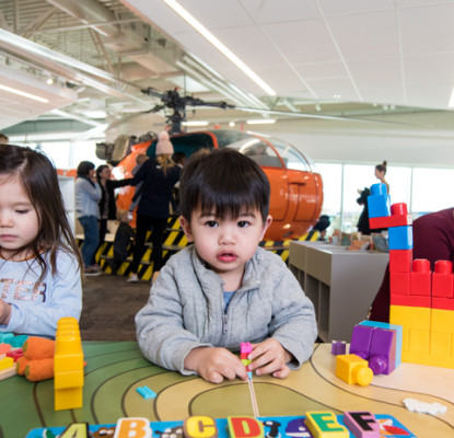 Photograph of of three children playing with blocks and alphabet activities. 