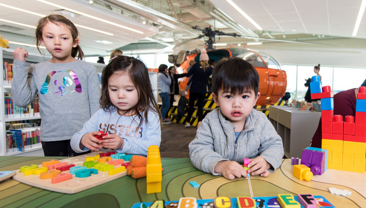 Photograph of of three children playing with blocks and alphabet activities. 